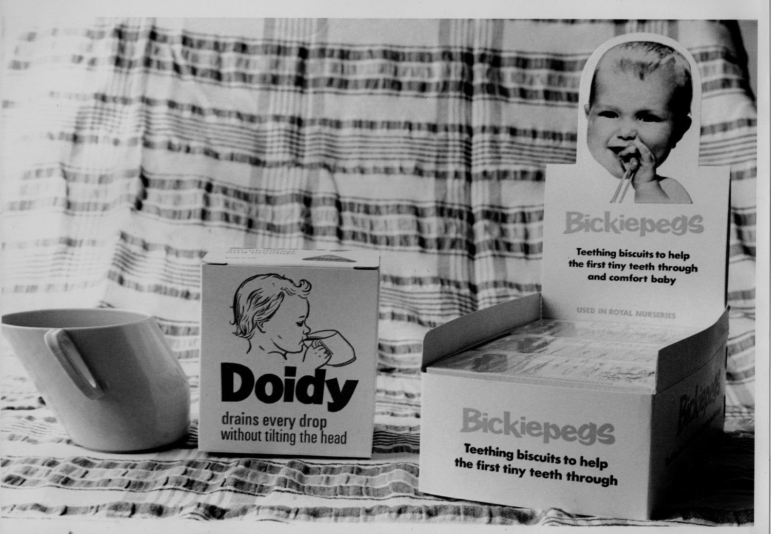 Vintage baby care products including Doidy and Bickiepegs packaging on a checkered fabric background.