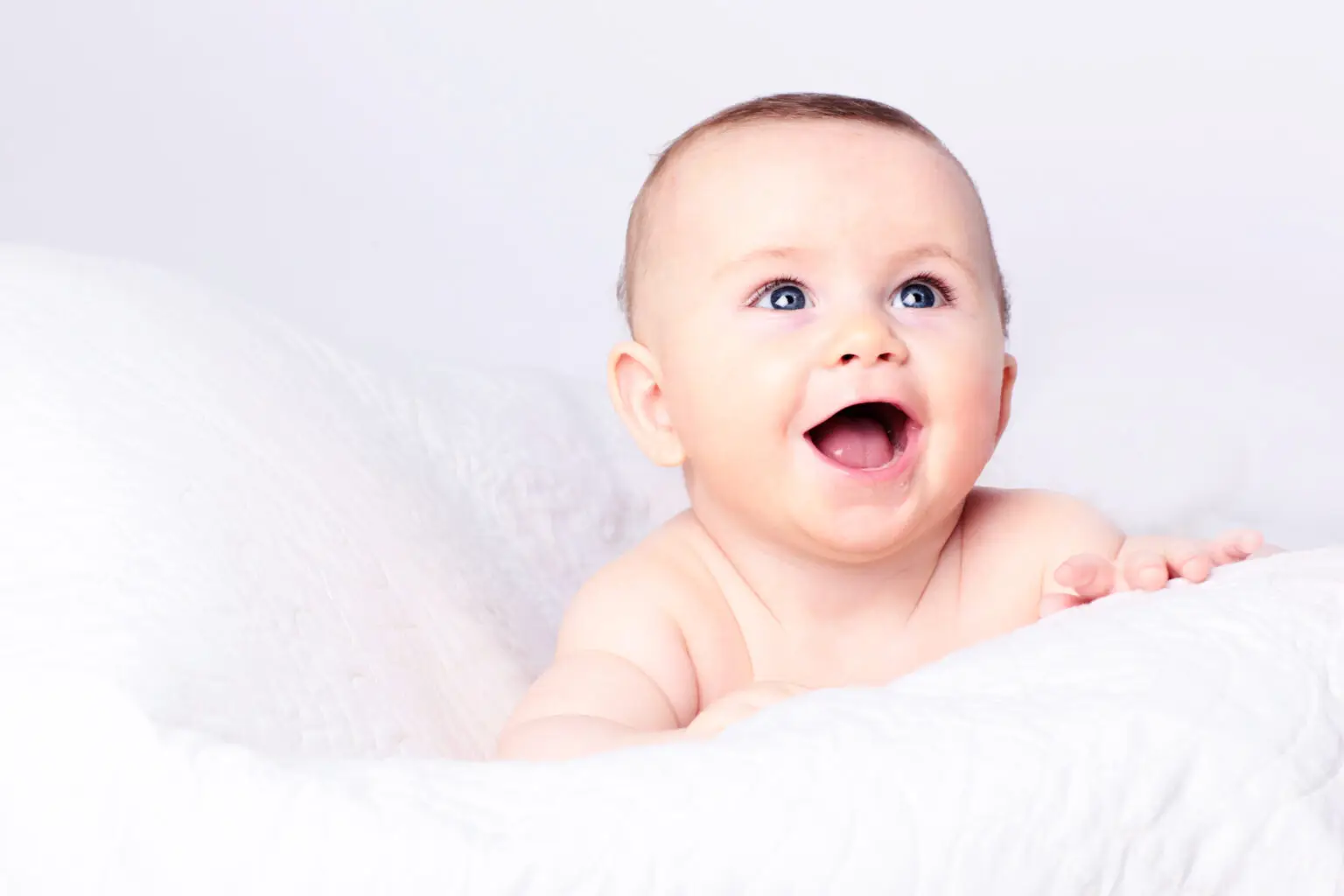 Baby smiling happily in a white background.